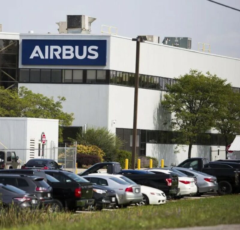Exterior photo of building with AIRBUS logo and cars in the parking lot in front of building